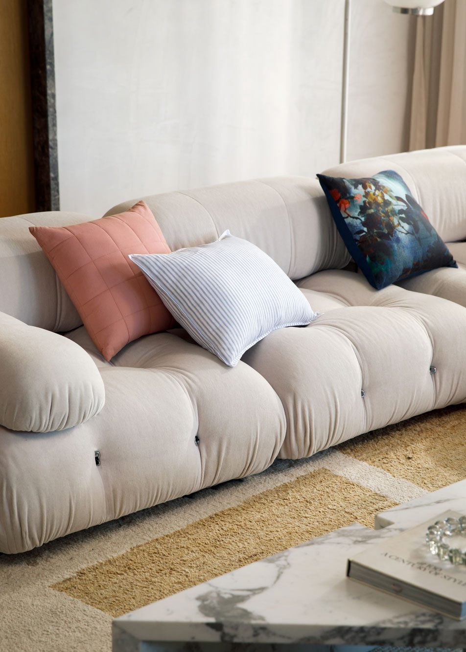 Three cushions of different colours and sizes stacked on a lounge